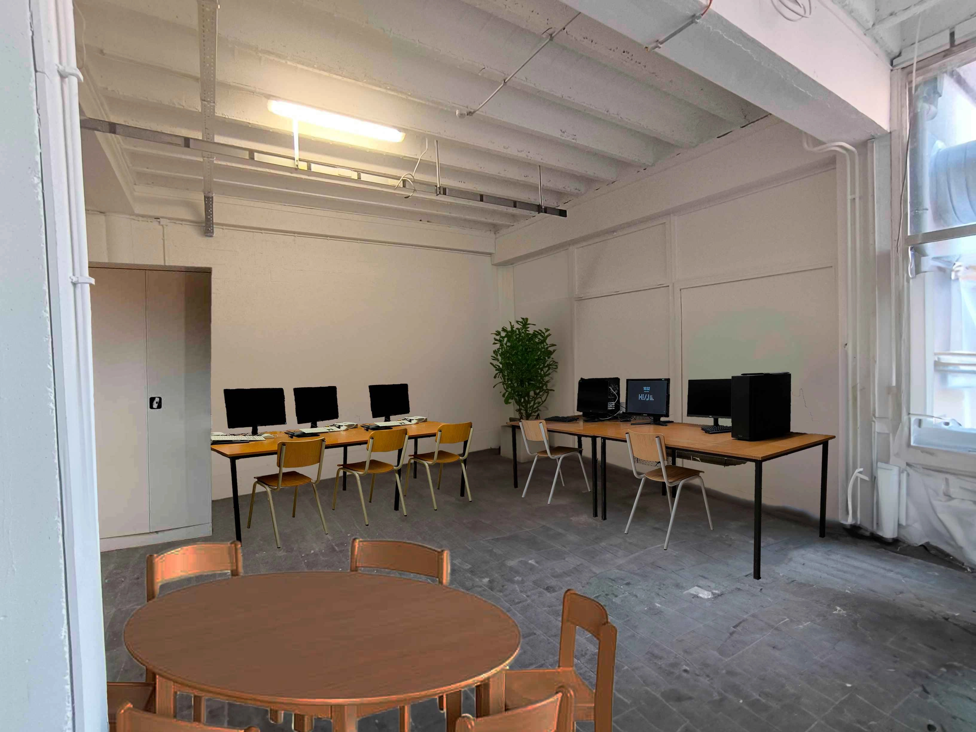 Image retouchée, montrant une vue du fond du local. Sur la gauche, il y a une table avec des PC ainsi qu'une armoire métallique. Juste devant la caméra, il y a la même table ronde que sur la photo précédente. Sur droite, une autre tables est occupée par des PC. Dans l'angles des 2 murs, il y a une plante.